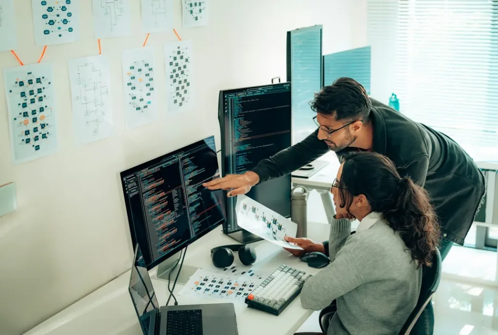 Two developers reviewing code together on desktop monitors